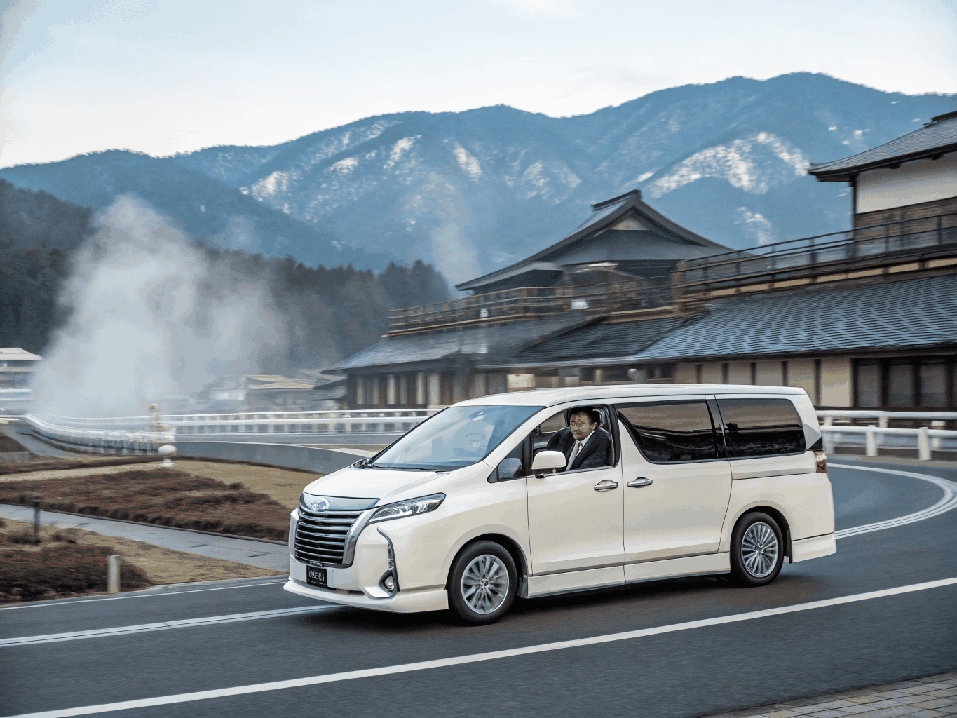 Private travel charter van cruising along a picturesque mountain road in Kyushu